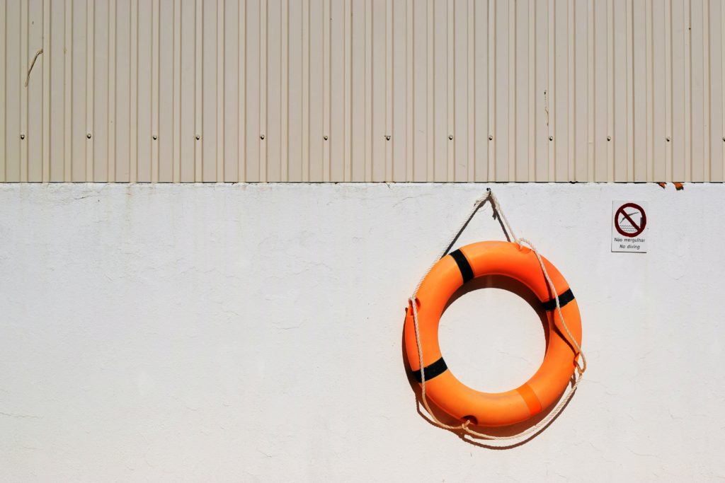 Orange life ring hanging on white wall