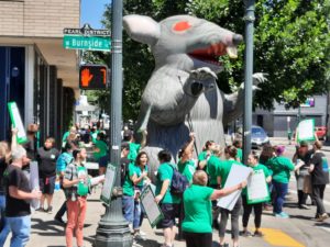 Members rally in solidarity in front of giant rat
