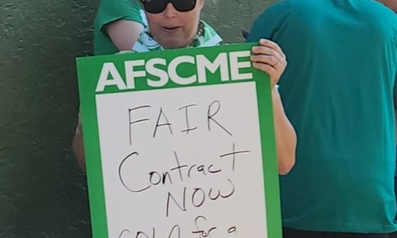 Woman holding sign Fair Contract Now COLA for a living wage