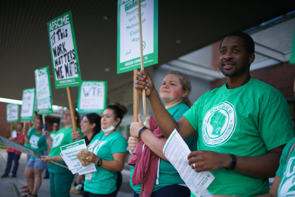 Union members in green tshirts holding picket signs