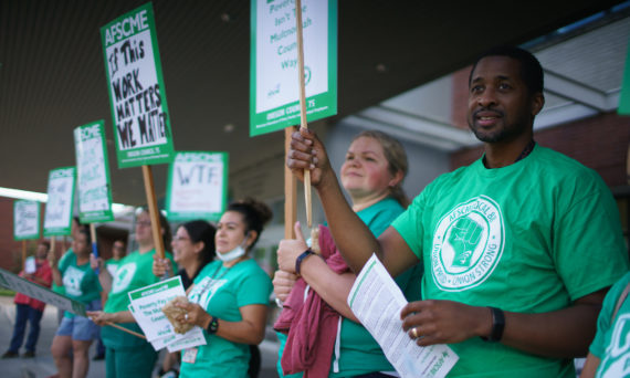 Union members in green tshirts holding picket signs